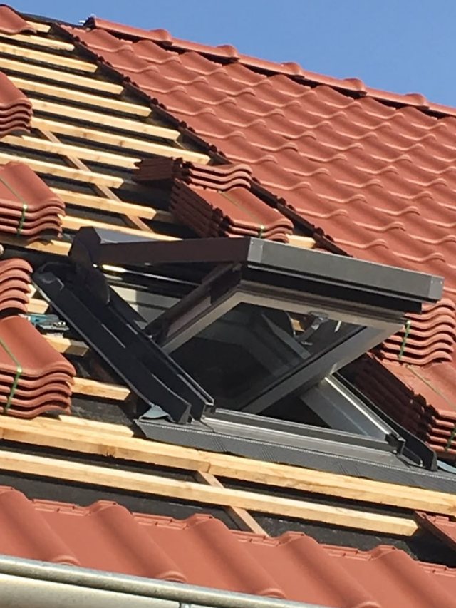 Neu eingebautes Dachfenster in einem Ziegeldach während der Eindeckung